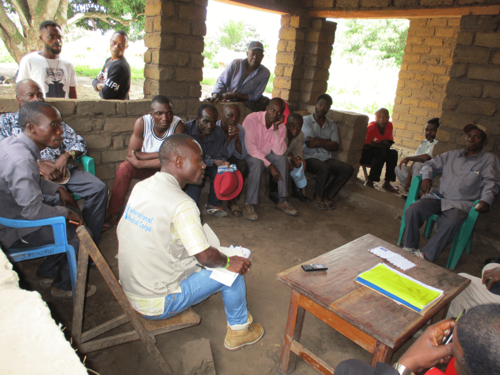 Mussa (lower left) helps lead a community meeting in Lumbwe village in South Kivu province.