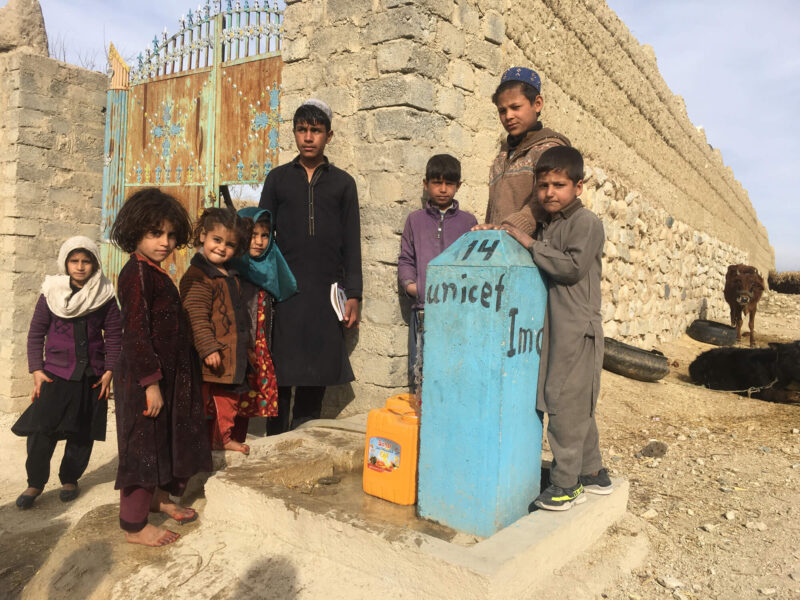 Children in Afghanistan stand next to a tap where they get clean water daily. With support from UNICEF, International Medical Corps constructed a solar-powered supply system that provides safe water to people in Nangarhar province.