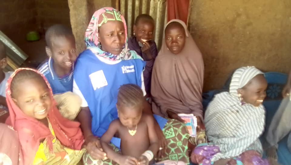 An International Medical Corps social worker visits Falmata (center) at her home to check on her after her surgery.