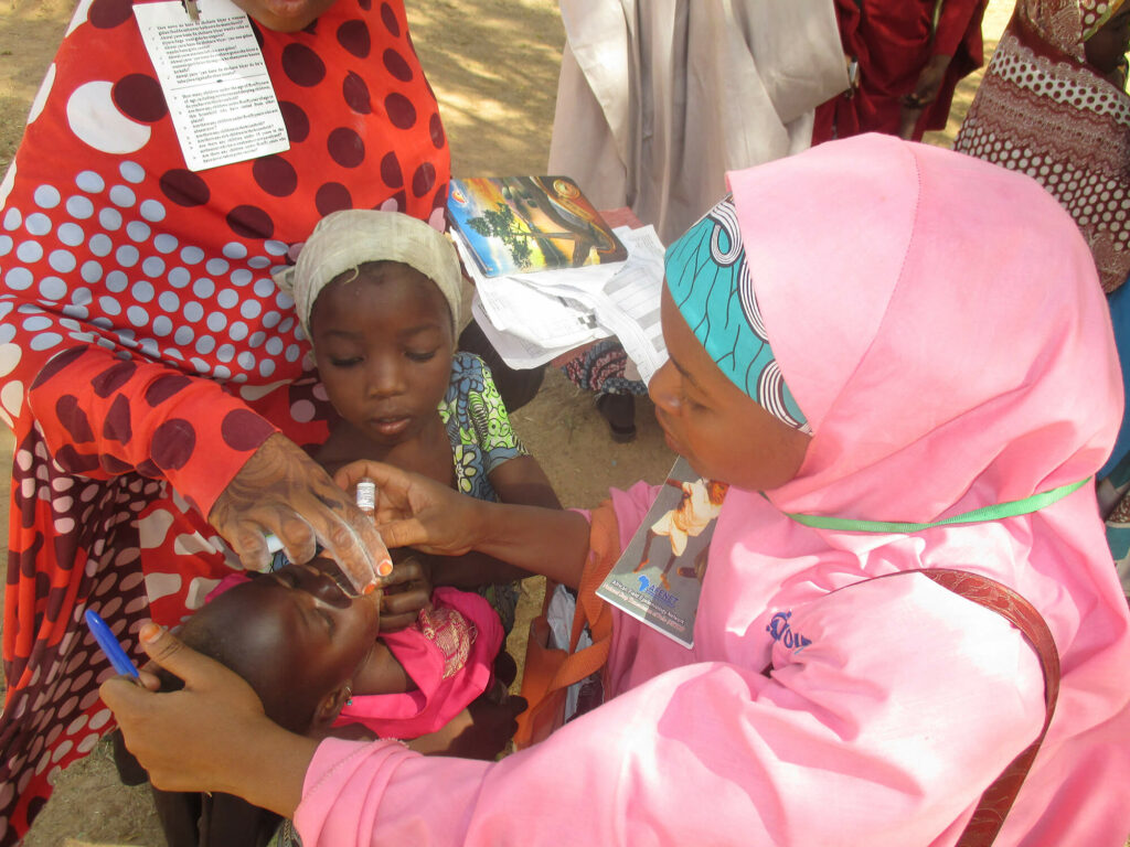 A polio eradication worker administers an oral polio vaccine to a child in Nigeria.
