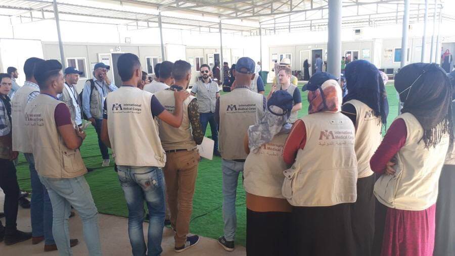 Dr. Furat (center) during a July 2018 orientation for community health workers at the start of a scabies prevention campaign in Hammam al-alil camp.