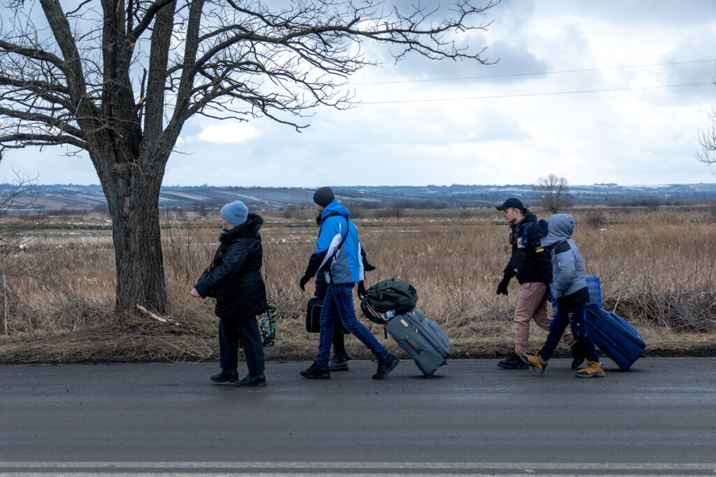 A group of Ukrainian refugees walk on the roadside after crossing the Siret border crossing on their way to buses chartered in Romania to take the new arrivals to accommodation in neighbouring villages or to different cities in Romania and Europe on March 05, 2022 in Siret border, Romania
