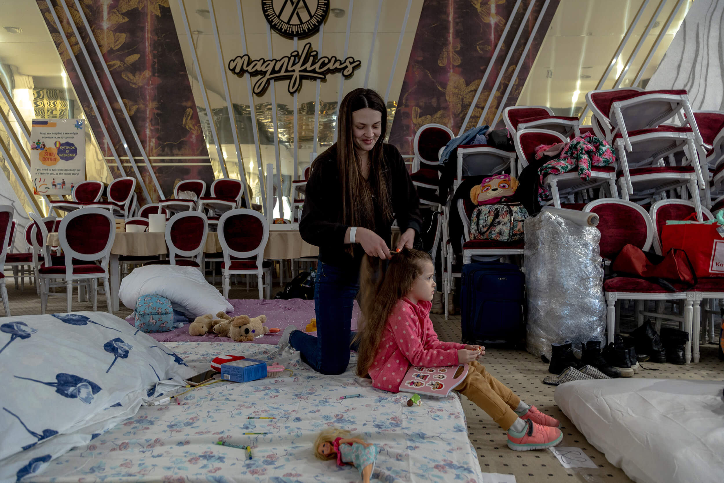 A woman combs her daughter’s hair inside a hotel where people arriving from Ukraine can rest for as many days as they want until they leave for their destination countries.