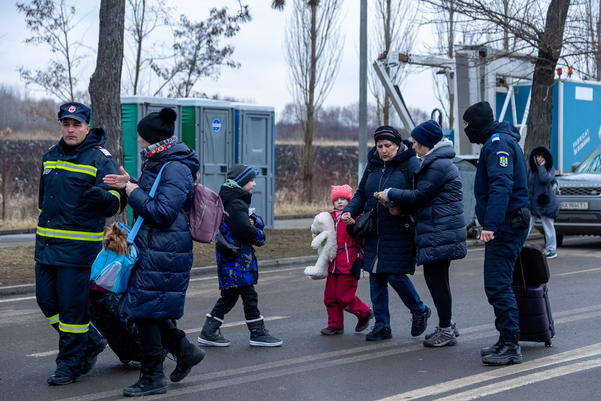 At the Siret border post, volunteers and police officers help carry the luggage of a newly arrived family from Ukraine.