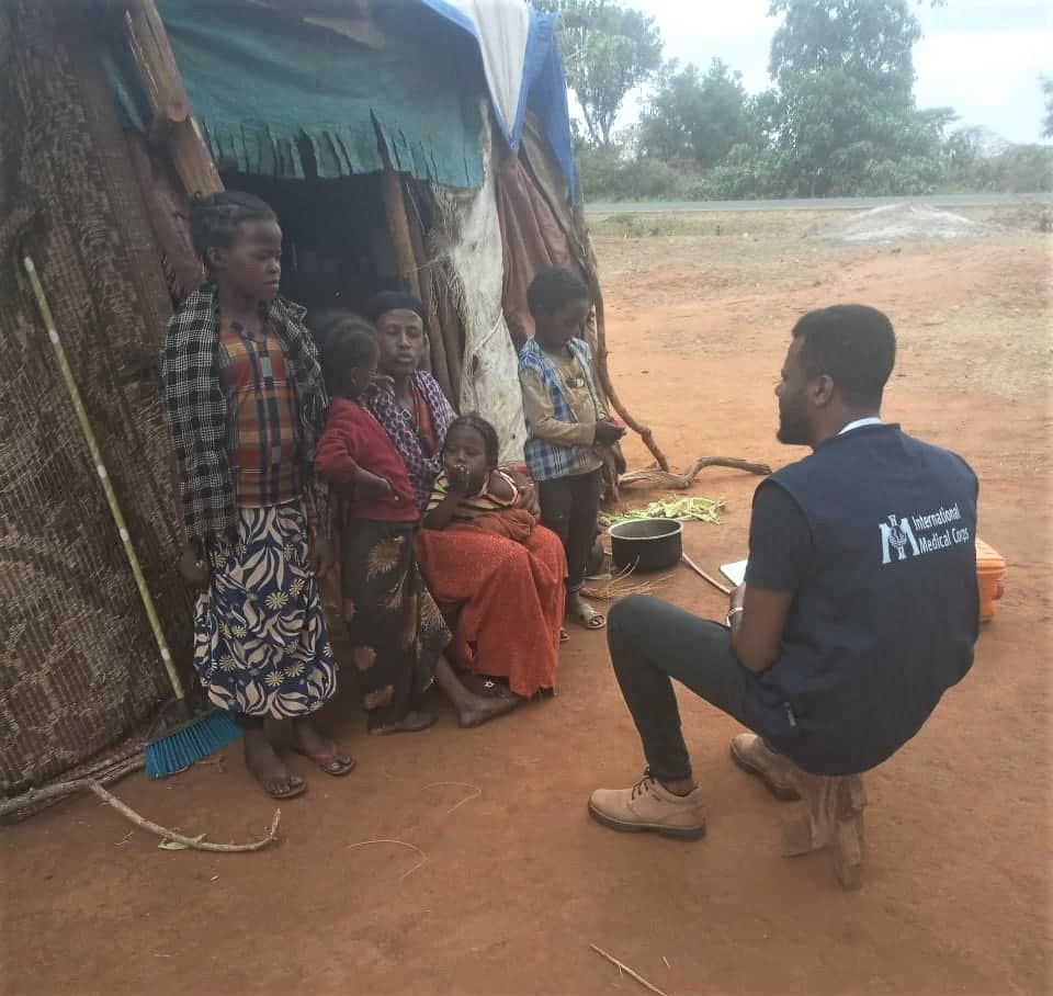 A WASH team member speaks to Radia and her children about good hygiene.