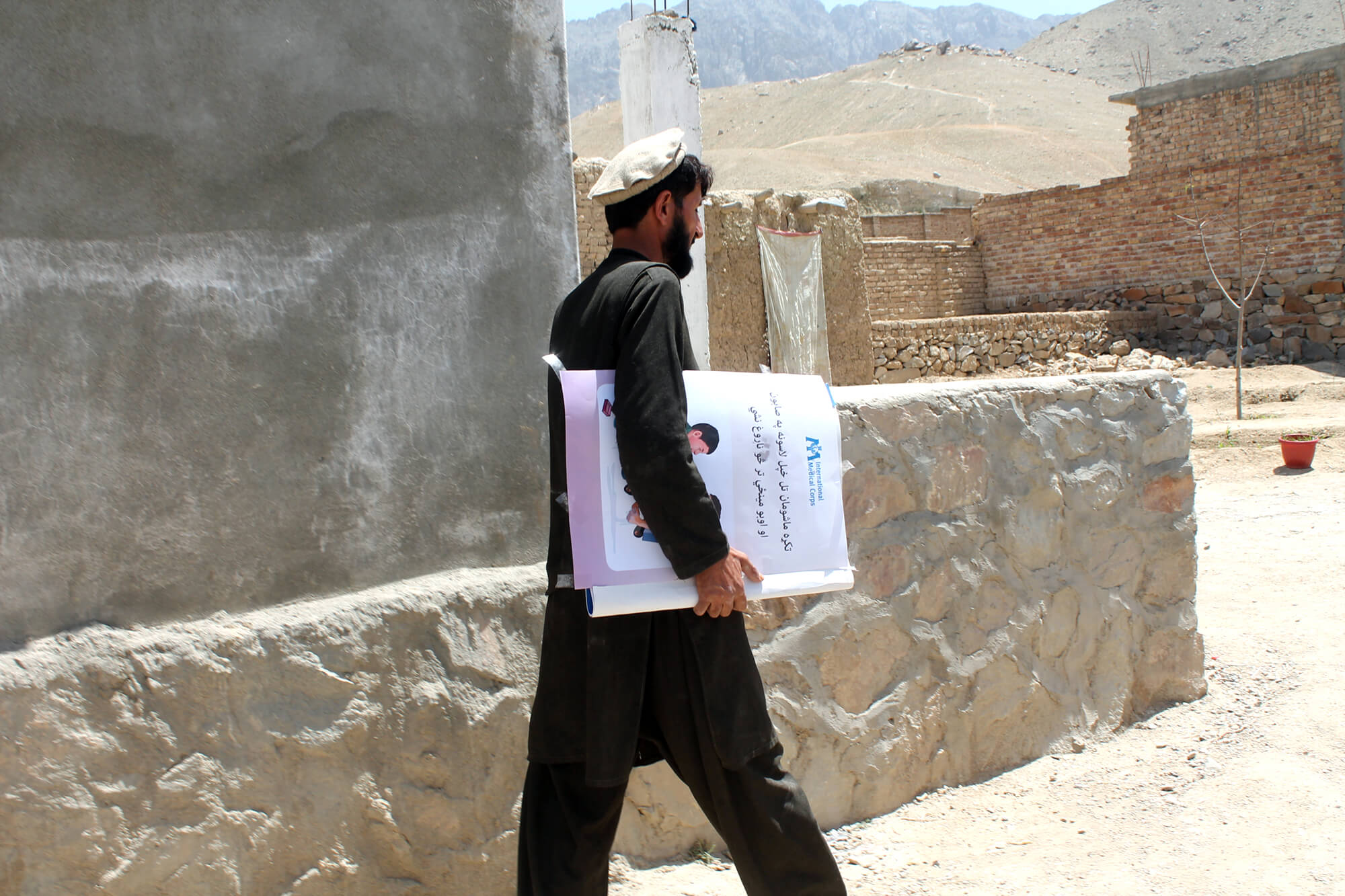 Community leader Haqmal carries educational materials to the health center in Dehsabz.