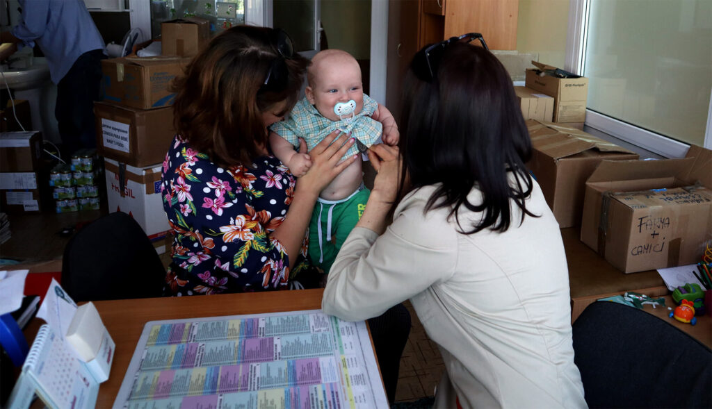 A doctor (right) cares for a child in Bucha Primary Healthcare Center in Bucha, Ukraine.