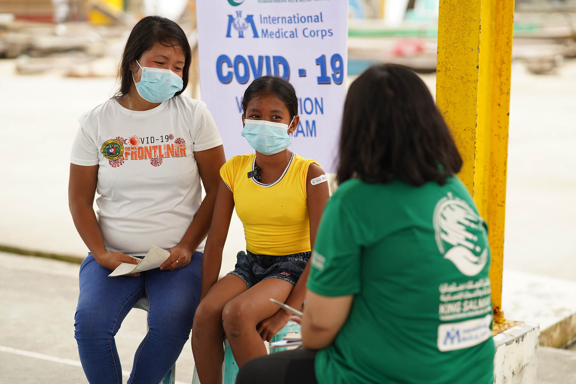 Mary Jovelle Santiago, International Medical Corps’ MEAL Officer in the Philippines, shares vaccination information with Queenie Escobido and her daughter.