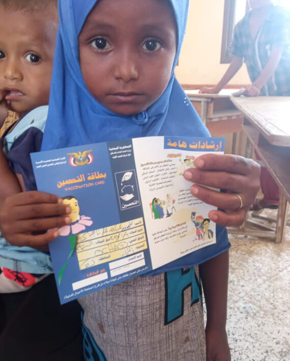 Shahid, a young resident of Al-Samasim village in Al Mukha district, proudly holds up her certificate of vaccination against measles after receiving her inoculation.