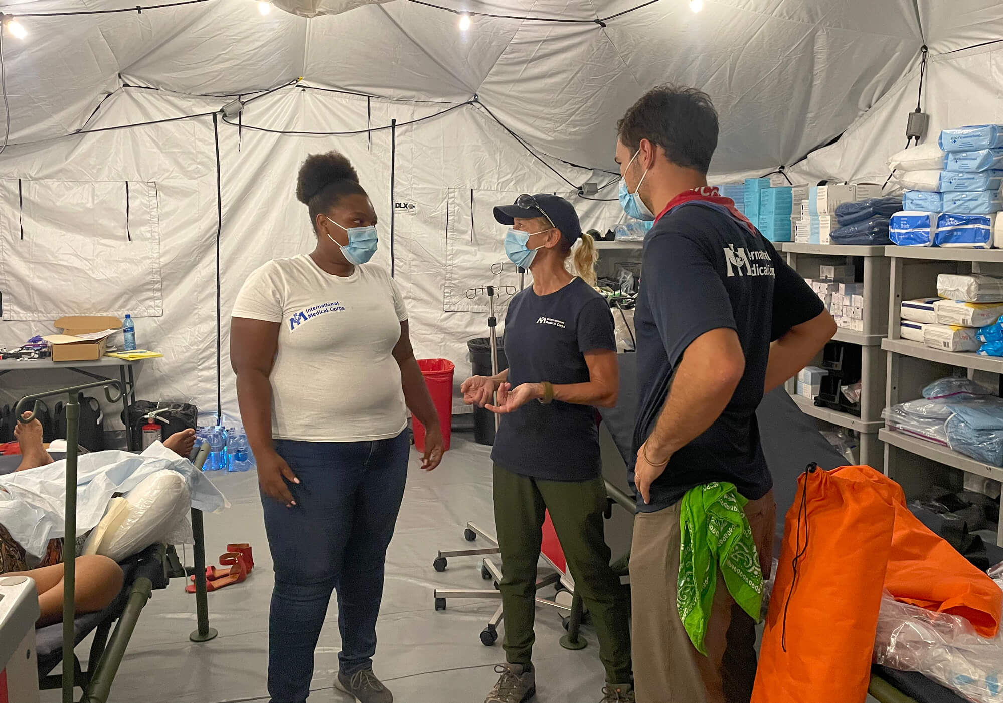 Dr. John Roberts (right) speaks with fellow team members Sue Mangicaro and Vanessa Delone Jean Louis inside the International Medical Corps field hospital in Haiti.