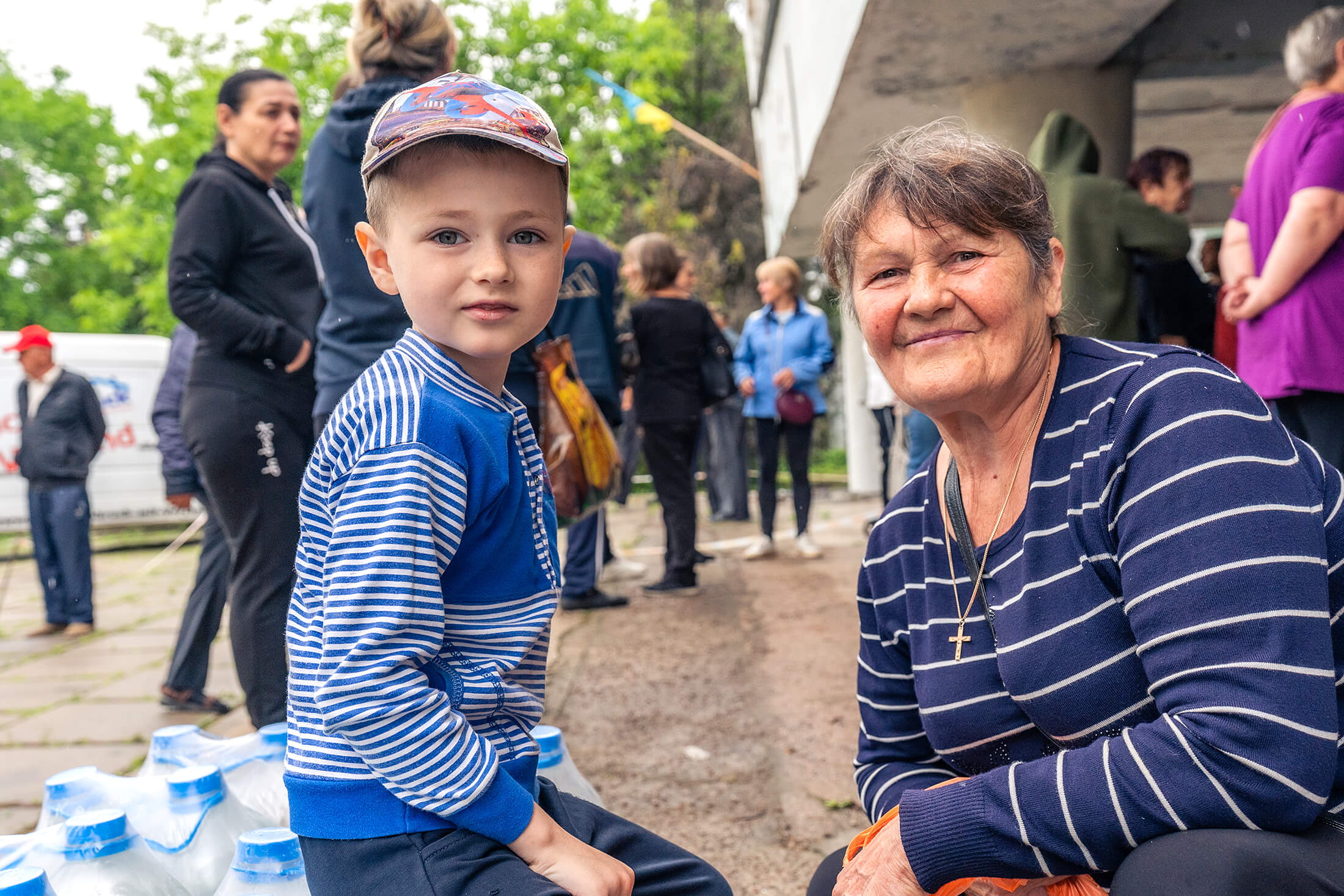 A young child and guardian in Novovoronsovka village receive clean water and supplies from International Medical Corps.