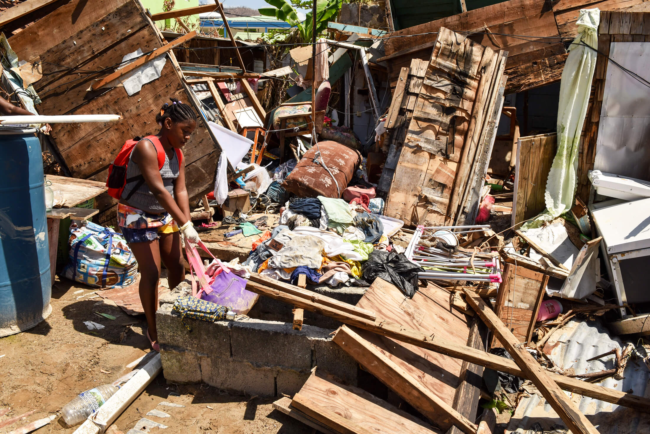 A woman picks through the remnants of a building destroyed by 2017’s Hurricane Maria, a Category 5 storm with winds of more than 175 mph that devastated communities across the Caribbean, caused more than $91 billion dollars in damage and killed more than 3,000 people.
