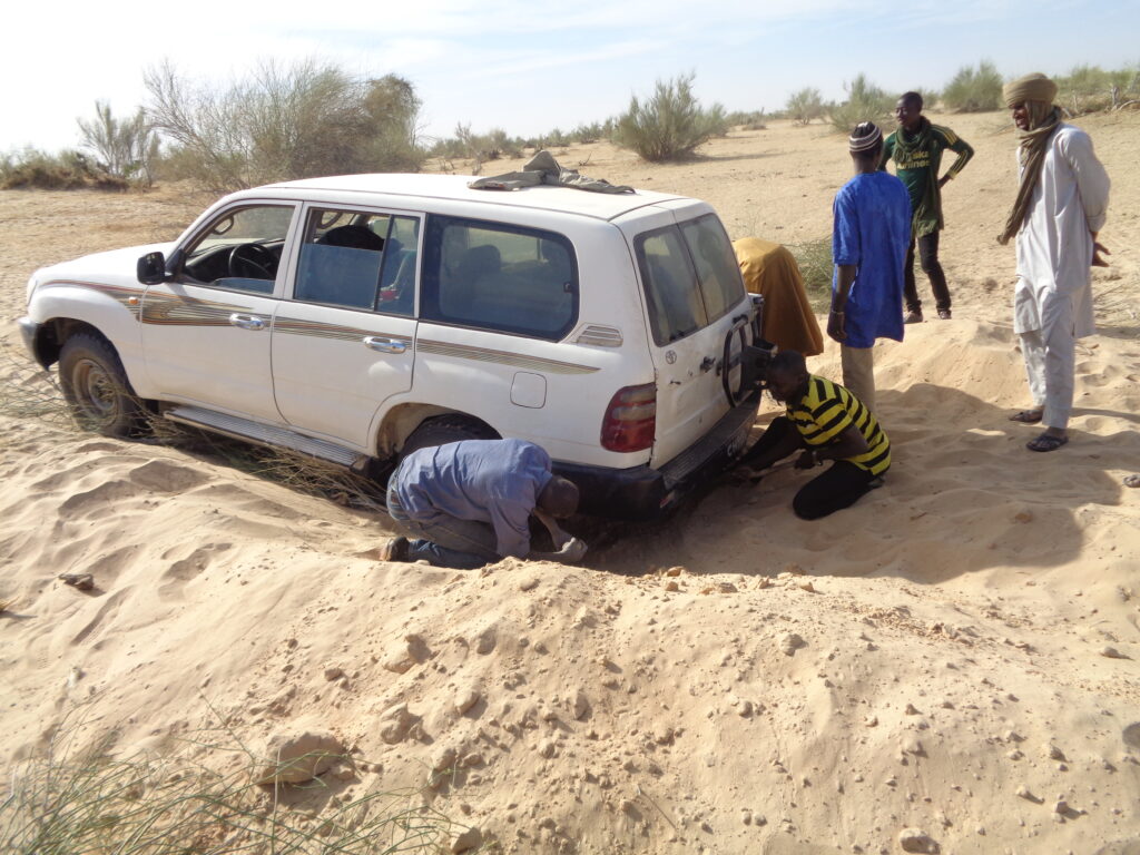 Ousmane Al Walil and community members in Hamzakoma help to dig the ambulance out of the sand.