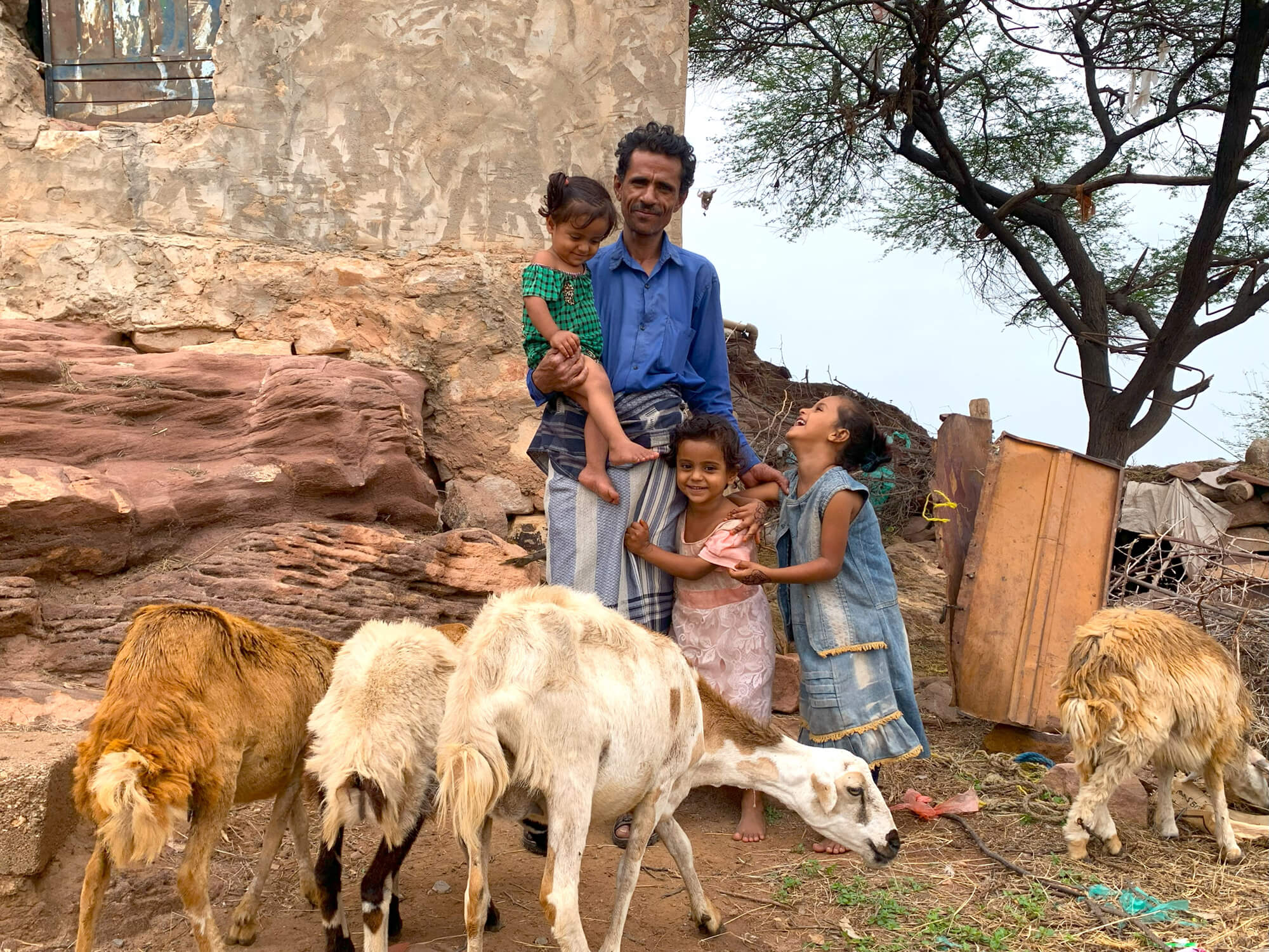 Hussein Masoud stands with his three children and their sheep in Khillah village, Yemen.