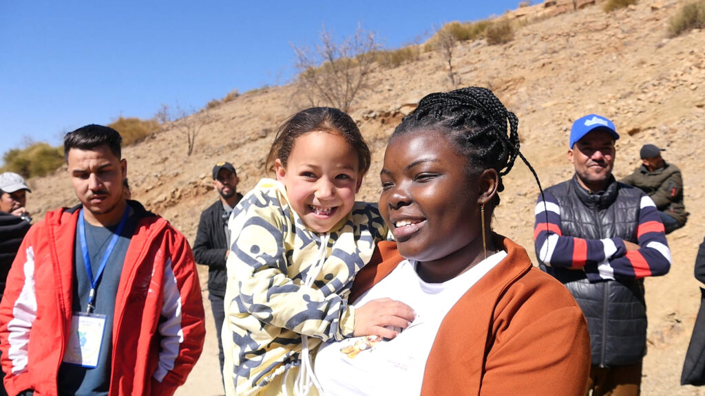 Staff member Dorah Lwanzo Kavira holds a child at the distribution site in the Ouneine region of Taroudant province, where our team provided winterisation kits and hygiene kits to earthquake-affected families.