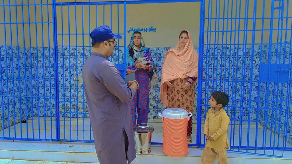 Khalida Laghari and her children meet with Kamran Shafi, Field Communications Officer with International Medical Corps, while collecting clean water from the water collection area.