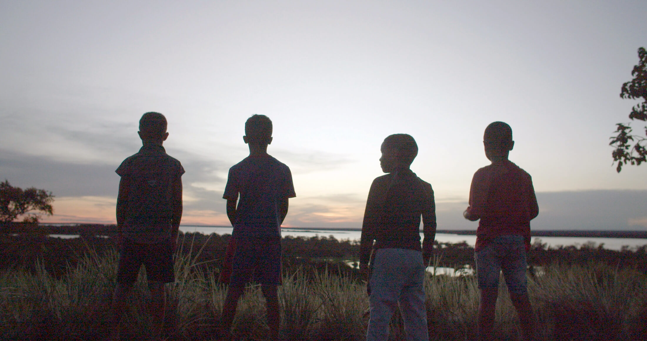 Children near Las Bombitas village play and watch the sunset over the Orinoco River.
