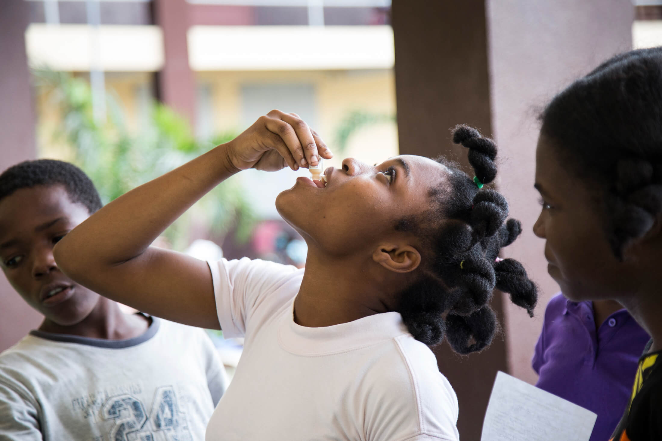 At a displacement site in Les Cayes, Haiti, a young girl takes the oral cholera vaccine during the campaign to vaccinate 800,000 people in Haiti after Hurricane Matthew.