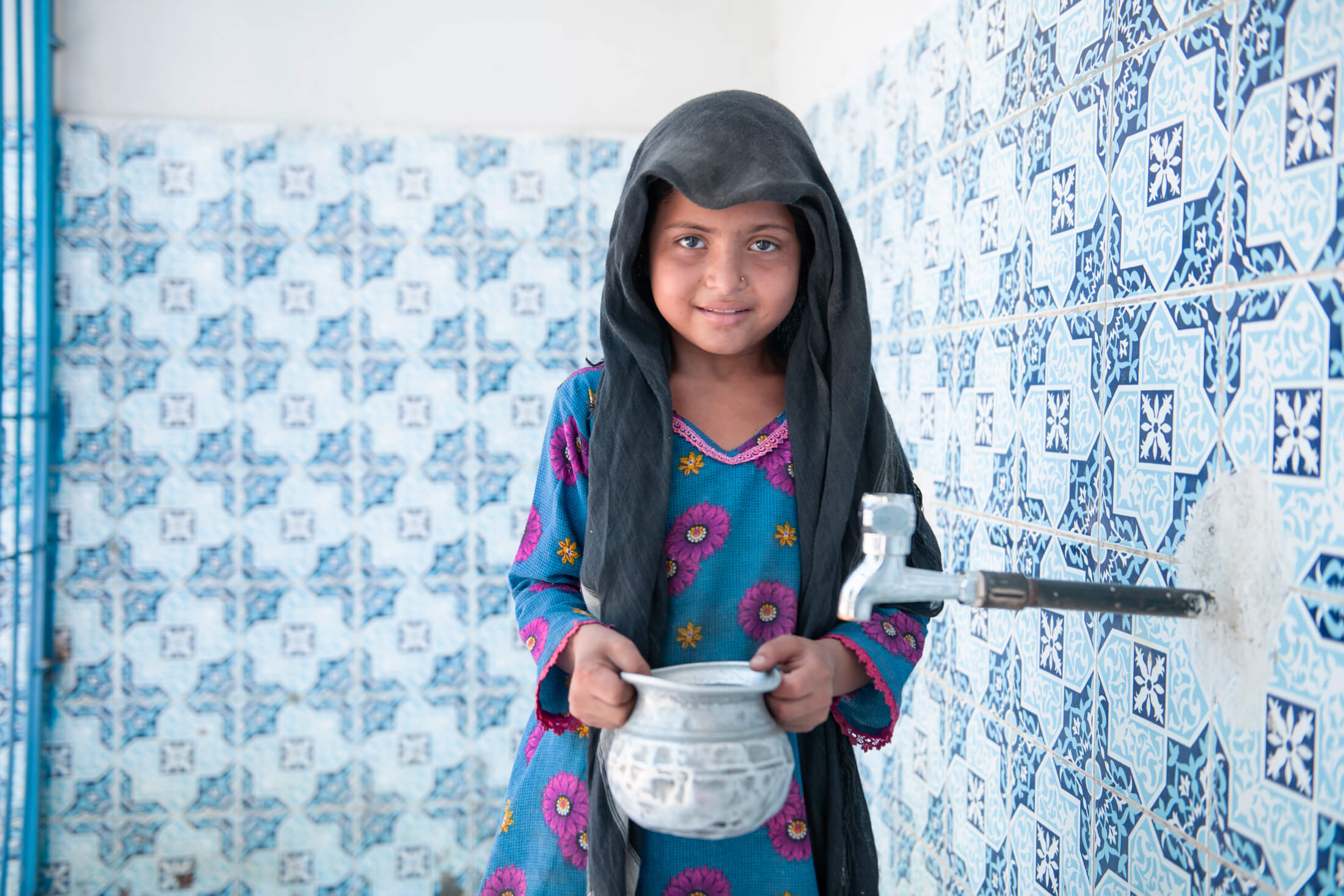 8-year-old Muskaan fills her water jug with clean water from the water supply system in Rindo Khan Laghari village.