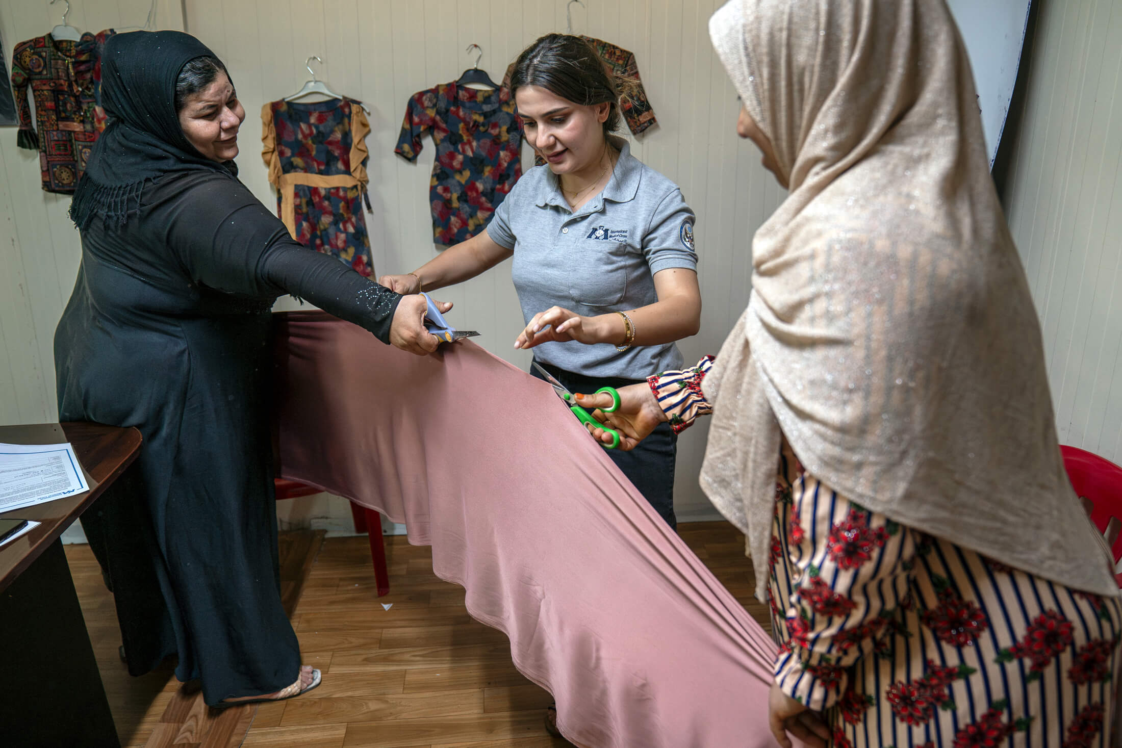 International Medical Corps Gender-Based Violence Manager Bahra Oshana (center) helps Fidha, 45 (left), and Mahsoma, 45 (right), cut fabric for their projects.