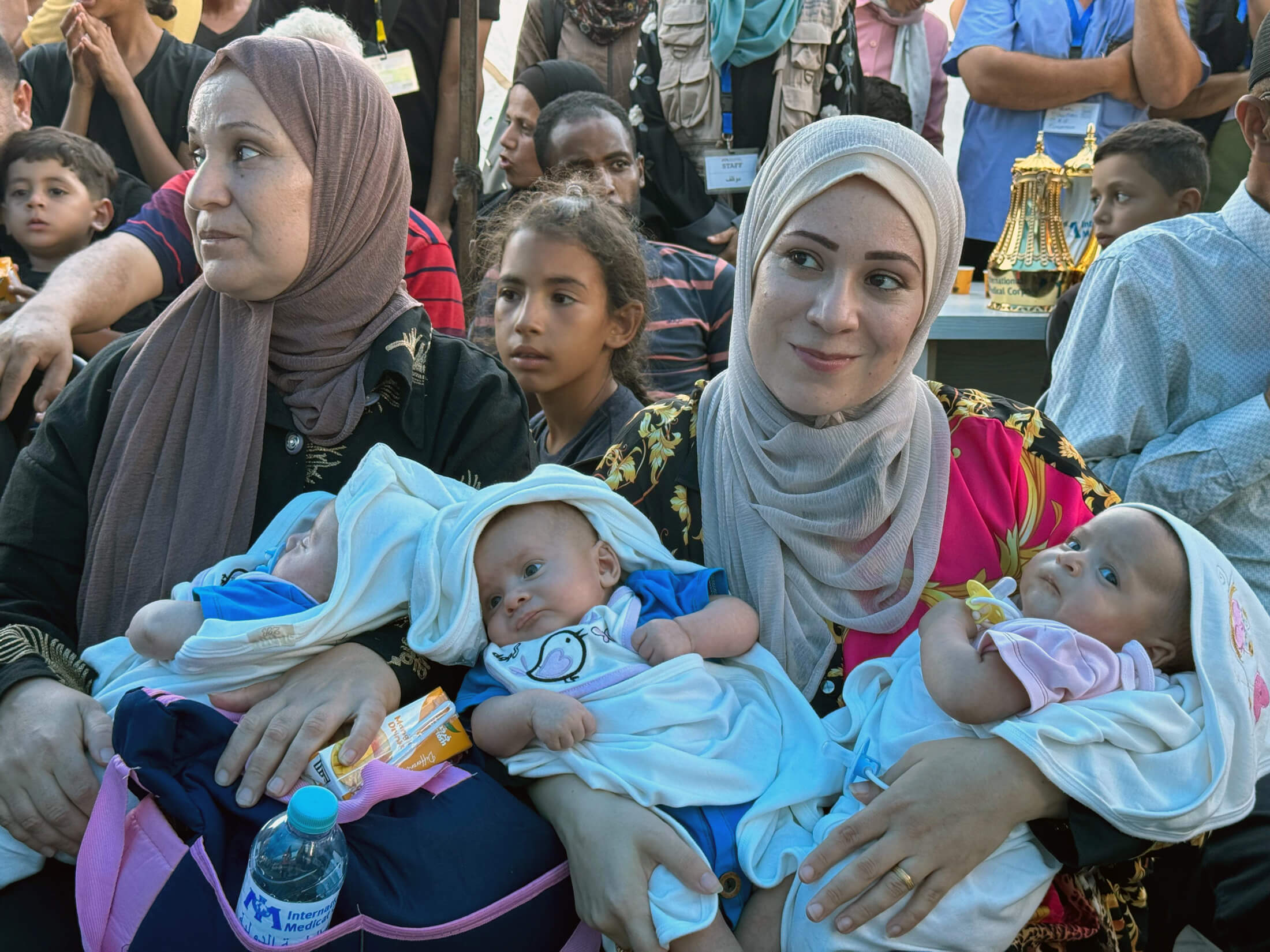 Ala’a (right) and her mother, Noha (left), hold the triplets at the party thrown by International Medical Corps staff to celebrate the family’s health.