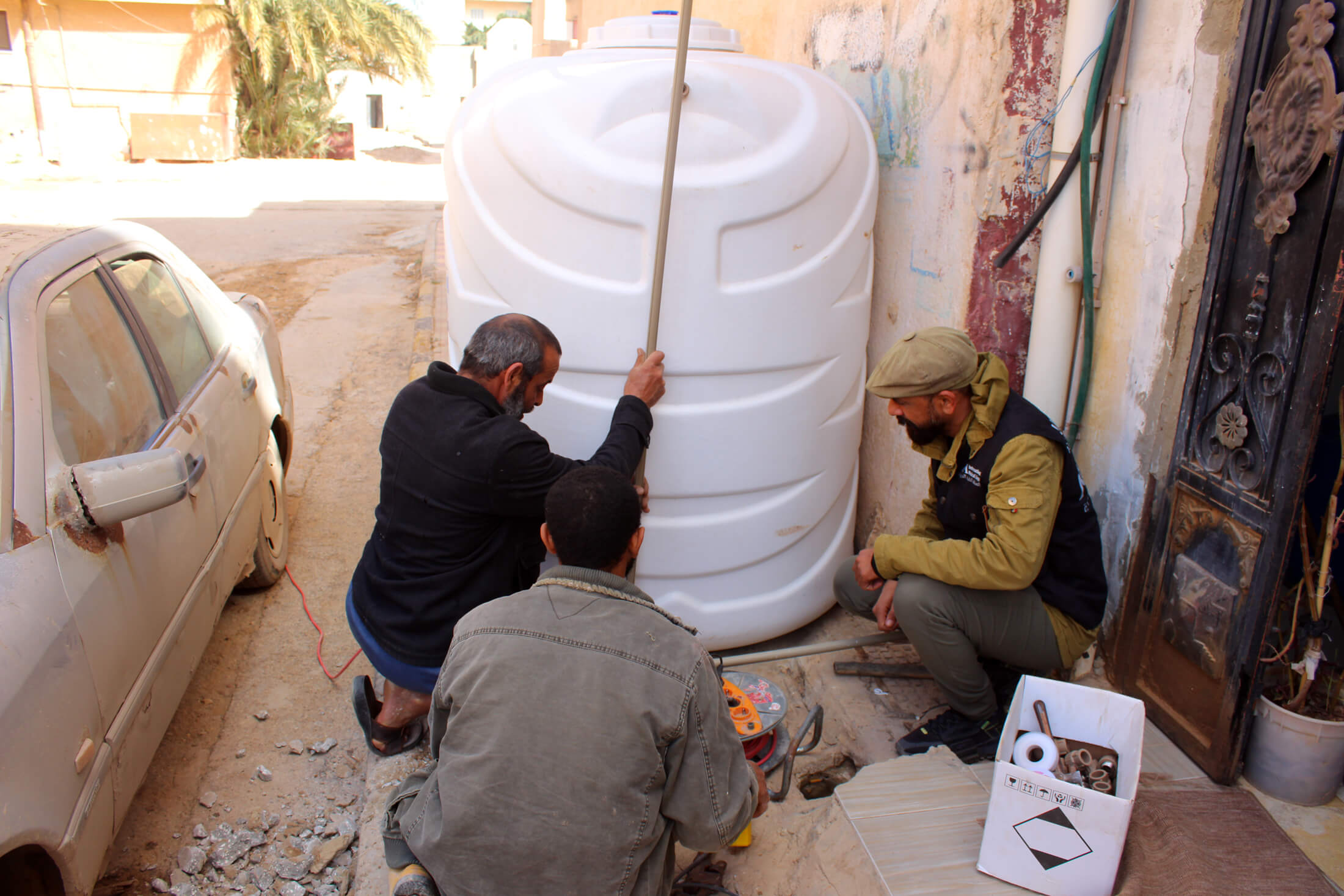 International Medical Corps WASH team members install a water tank in the Alsahil area of Derna, where many displaced people now live.