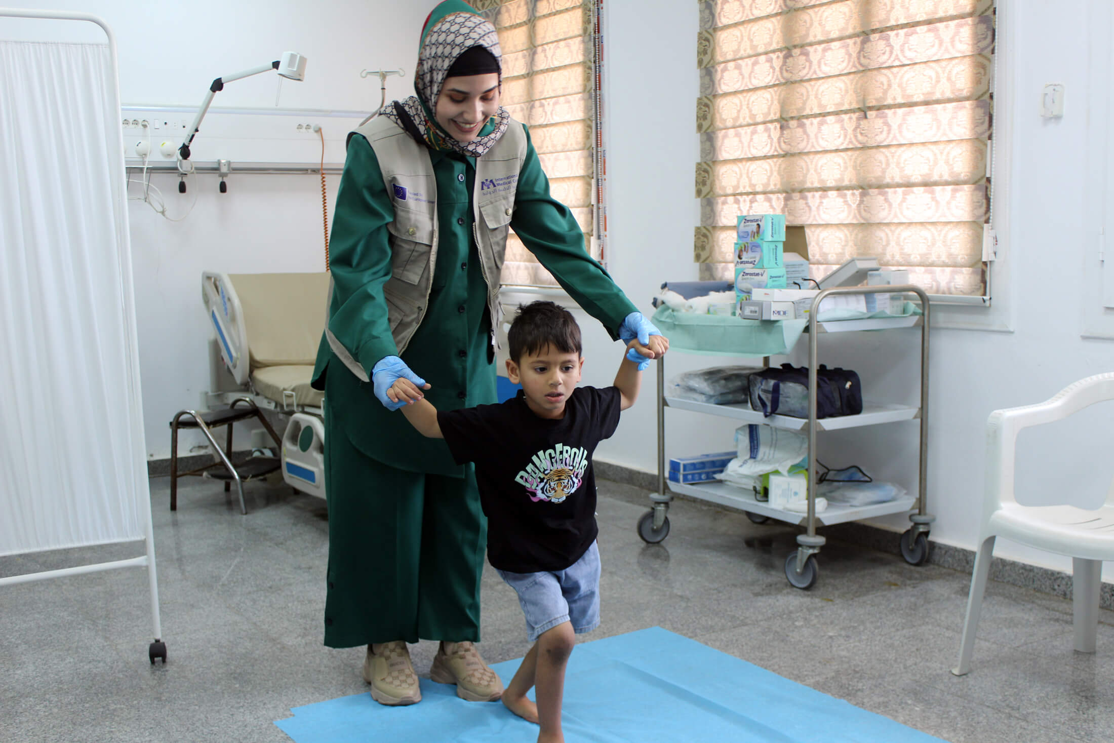 Dr. Safa Daw helps Abdulaziz walk during a physiotherapy session.