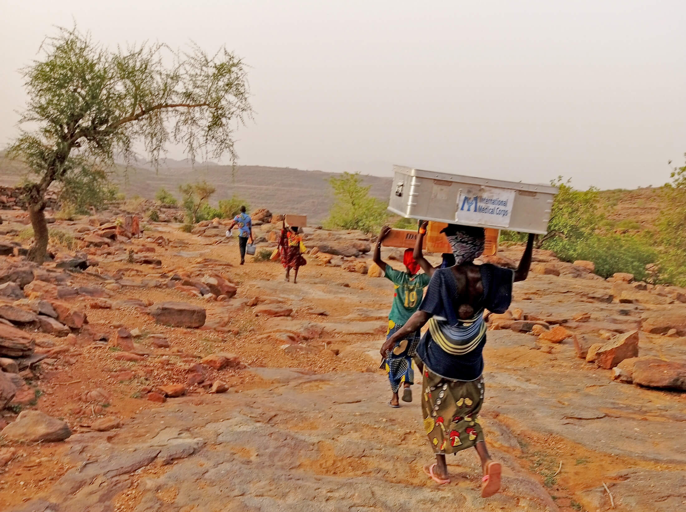 Members of our MMU and local volunteers carry health supplies to their village.