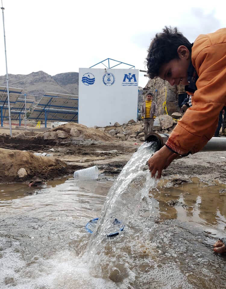 A local boy celebrates the new system’s first water flow.