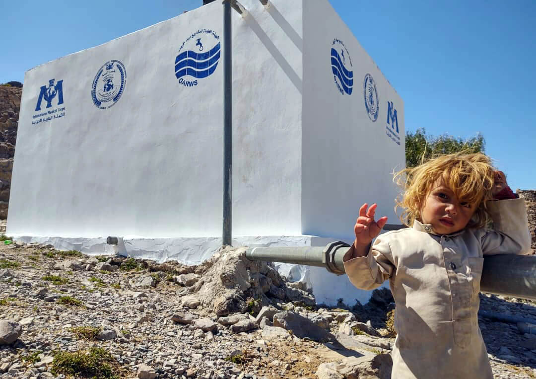 A child stands in front of the new water supply system in Al Kharbh subdistrict.