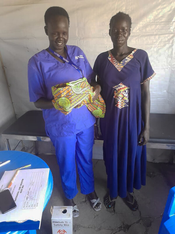 Midwife Sarah Anai Atong holds the baby she successfully delivered at our mobile medical unit, while she stands beside the baby’s mother, Nyawech Chamjok Lahm.