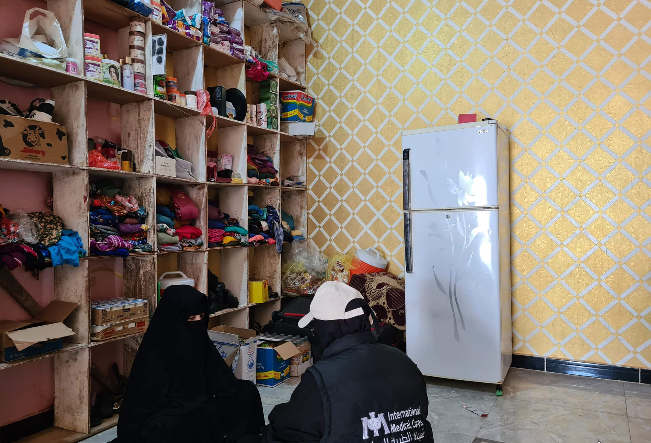 A CHW checks in with Afaf in her home, where she has established a small shop to sell goods to local women.