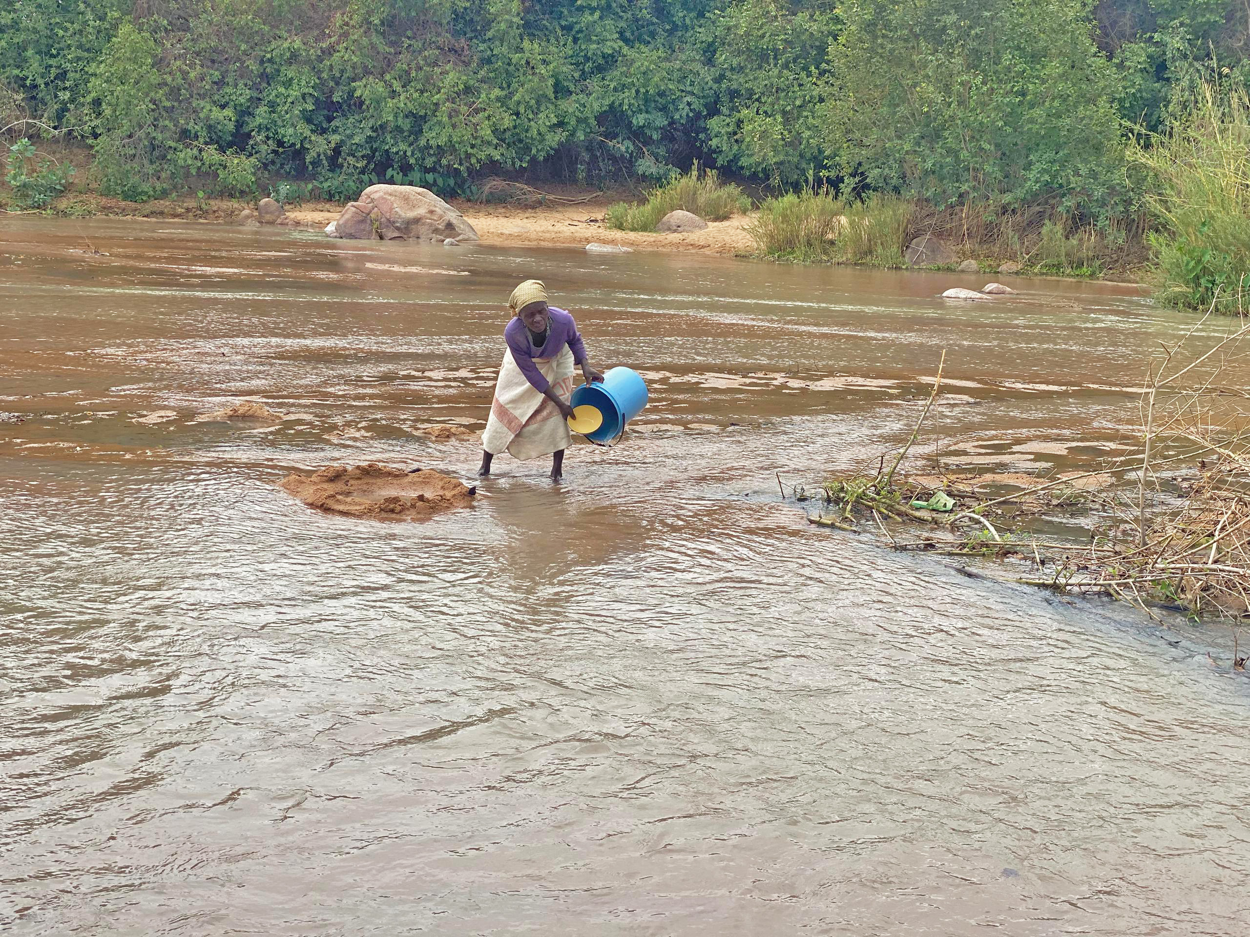 Mollen Kusereka collects water from Dewure River, relying on a makeshift filtering method to make it safer for her family’s consumption.