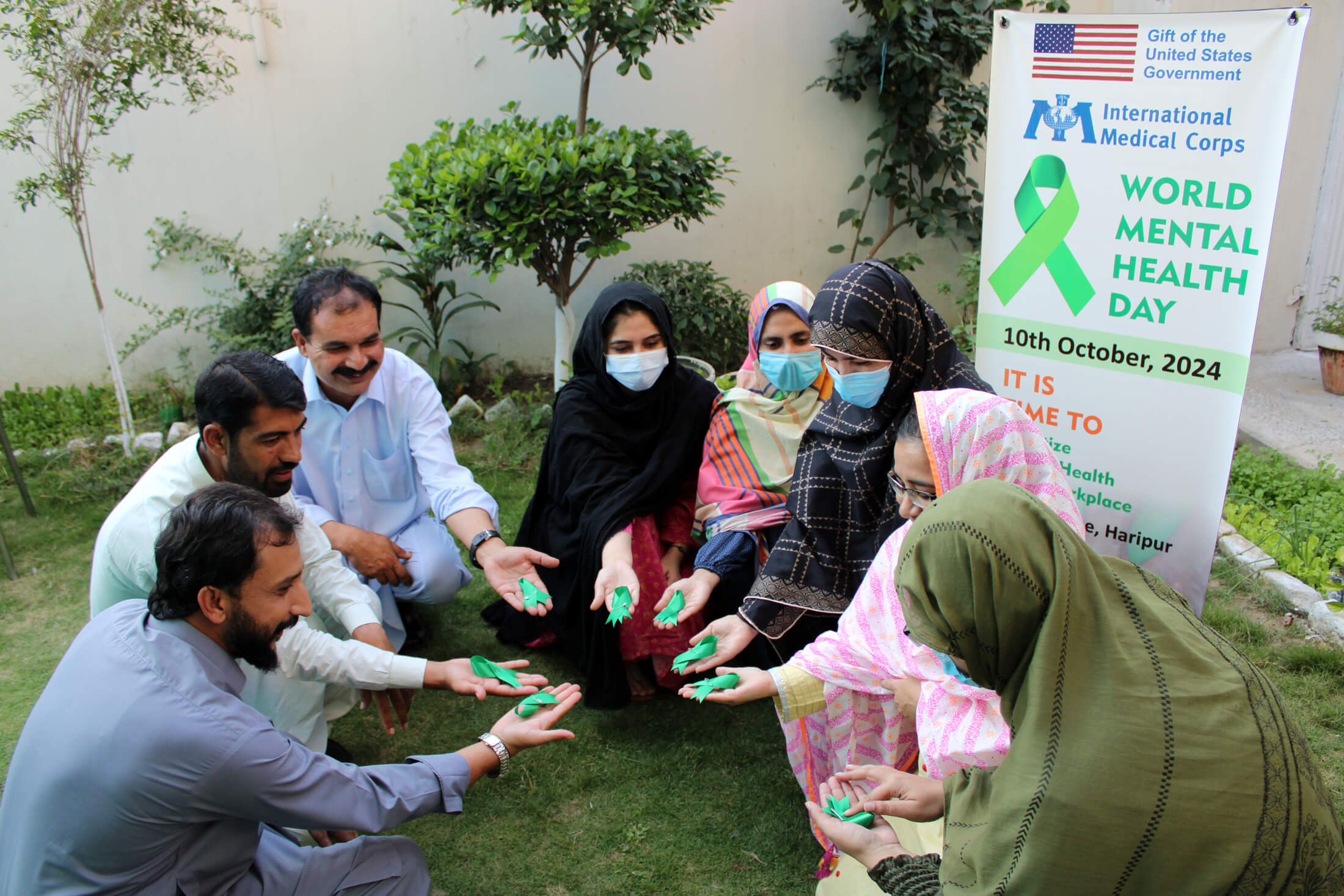 At the World Mental Health Day event in Peshawar, several team members hold green ribbons—an international symbol of mental health awareness—in their hands during an interactive group session.