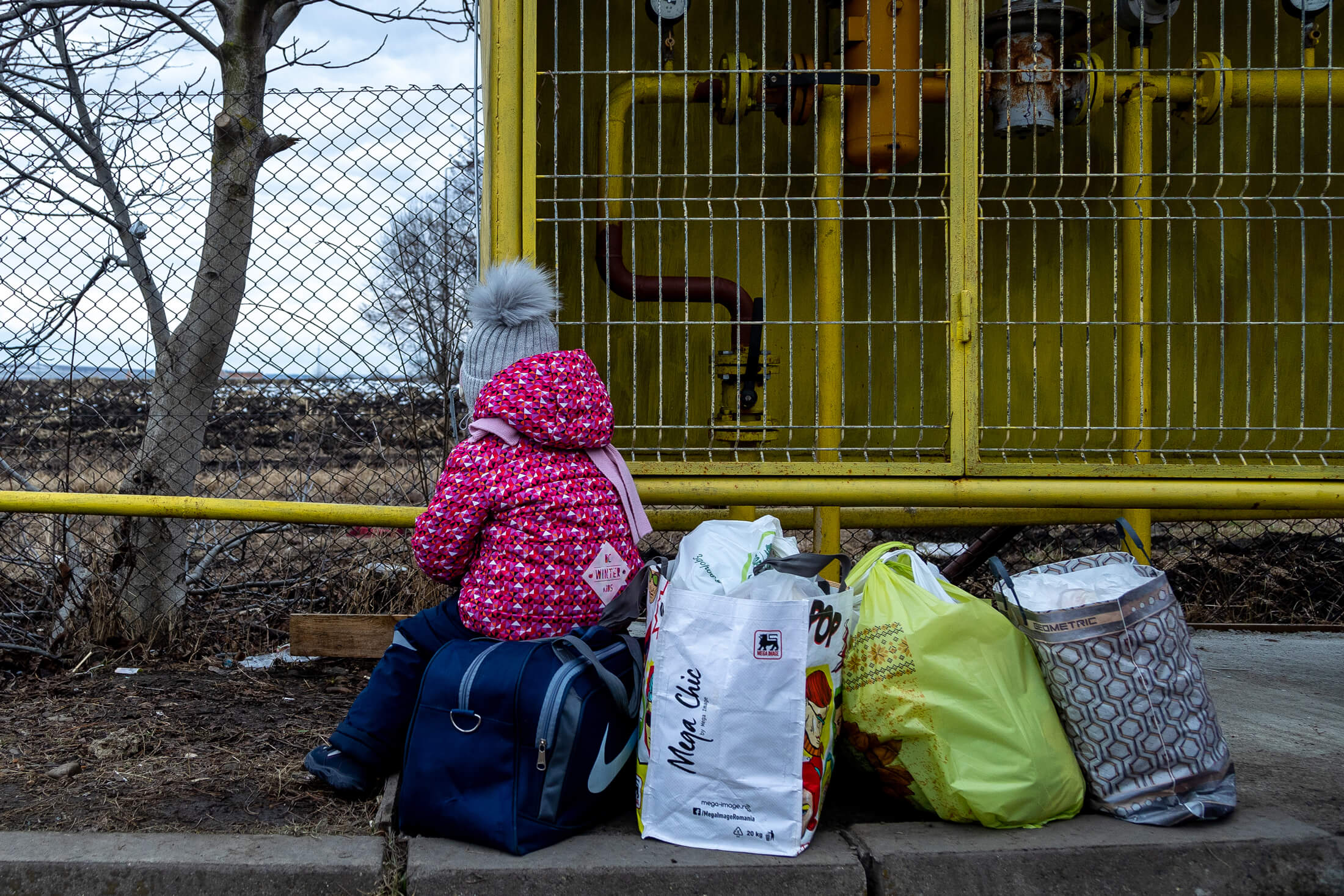 A two-year-old girl sits on her family’s luggage after they fled Ukraine in March 2022.