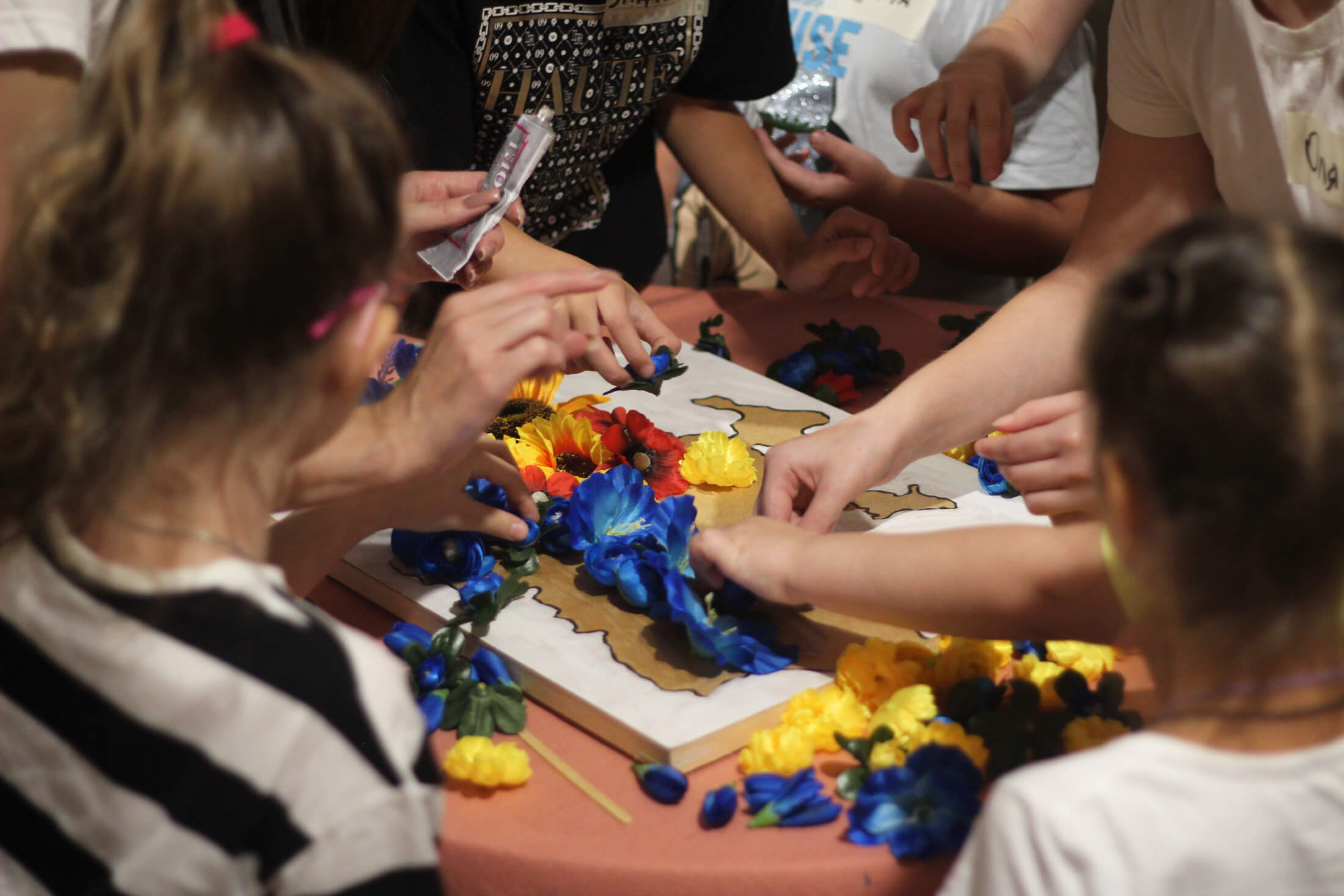 Displaced children from Bakhmut work together to decorate a map of Ukraine using flowers.