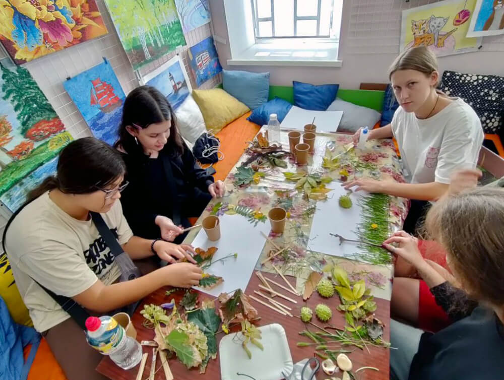 Olena and her peers use natural materials gathered outside to create art on the theme “colors of autumn” during a psychosocial support session.