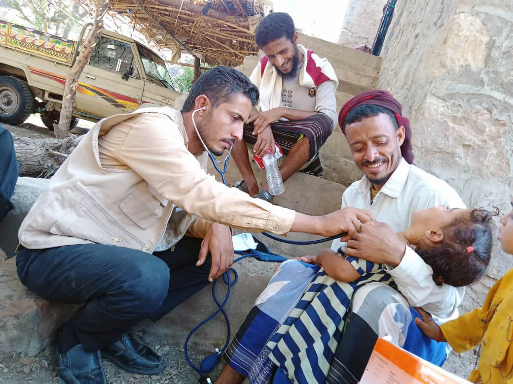 Parents in one of the affected villages in Al Dhale’e bring their children for medical checkups from members of the CRT.