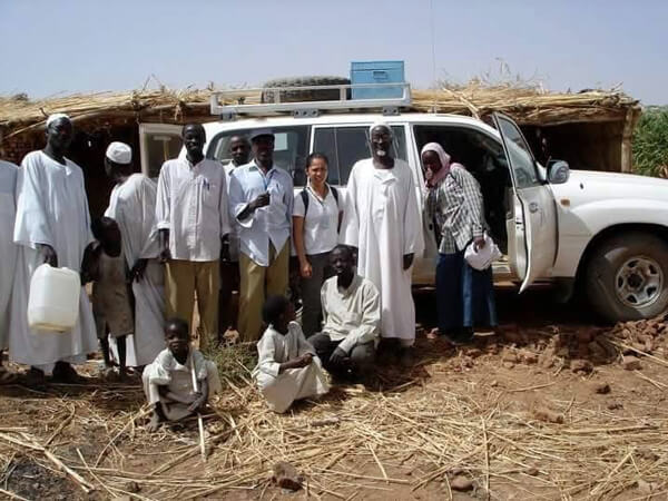 Dr. Bernardita Gaspar (center) with International Medical Corps staff members, community leaders and their families in 2006 outside one of our clinics in Darfur, Sudan