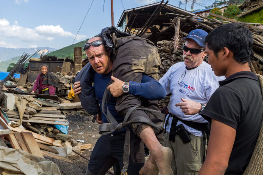 Dr. Michael Karch carries an injured man during our earthquake response in Nepal in 2015.