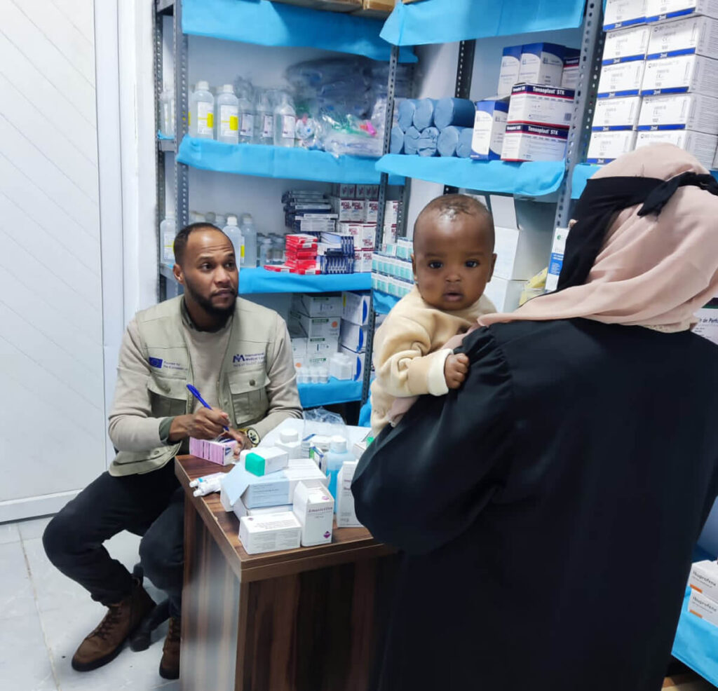 An International Medical Corps pharmacist meets with a Sudanese woman and her baby in the mobile medical clinic in Kufra.