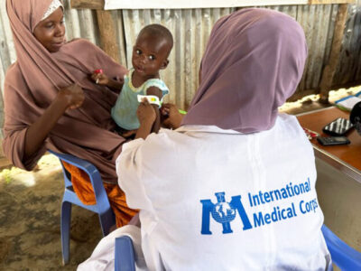 An International Medical Corps health worker takes Mohamed’s MUAC measurement while he sits in his mother’s lap.