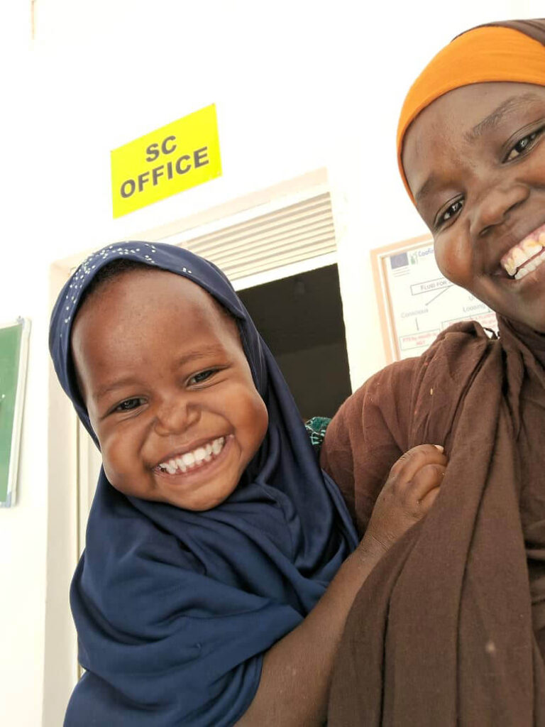 Rahma smiles widely in the arms of her mother, Mahadho, after being treated for malnutrition at Galkayo Referral Hospital.
