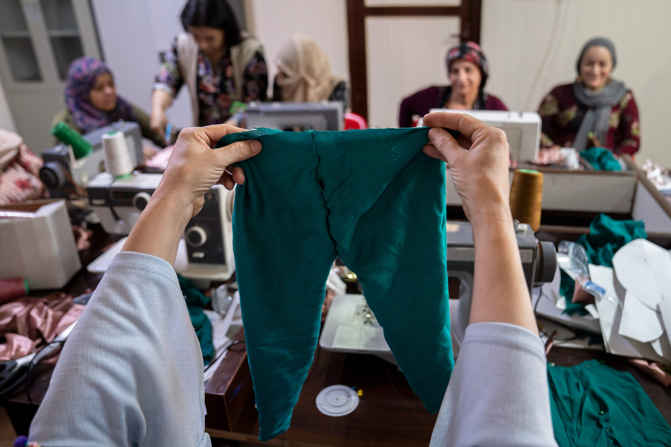 Suaad Mohamed Ahmed holds up a pair of pants she made during a tailoring lesson.
