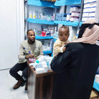 An International Medical Corps pharmacist meets with a Sudanese woman and her baby in the mobile medical clinic in Kufra.