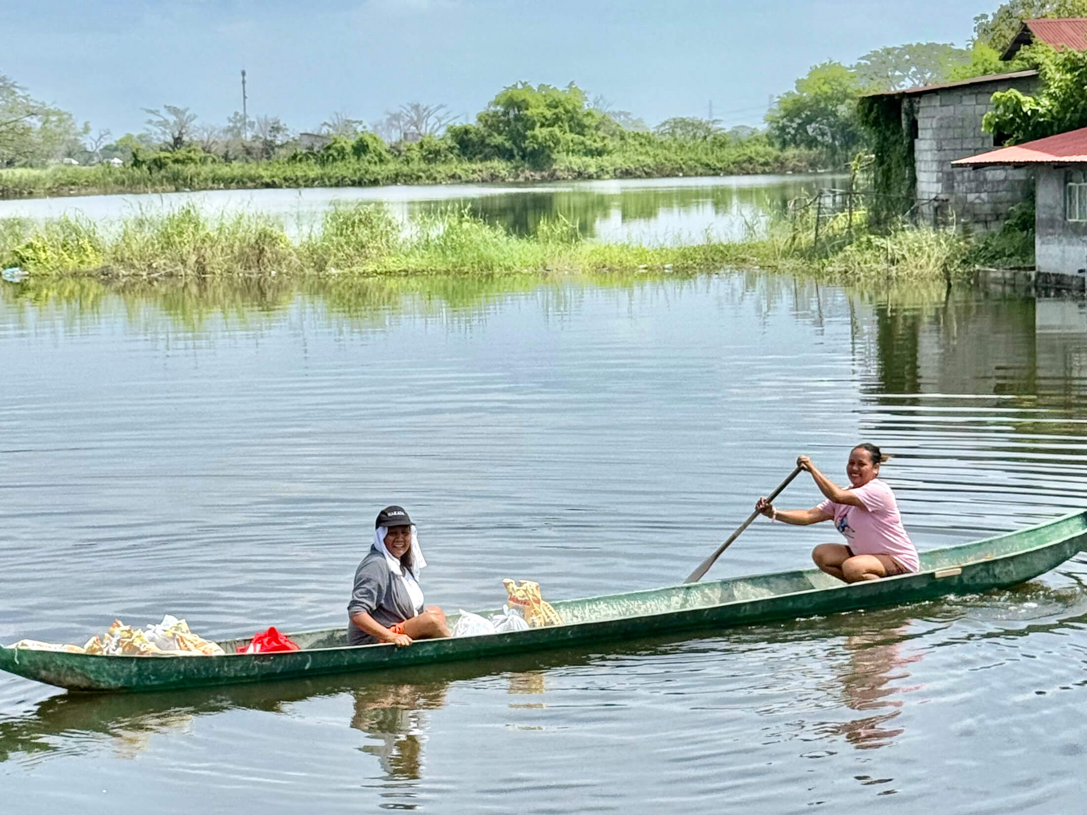 Residents paddle their boat home through floodwaters after receiving food kits.