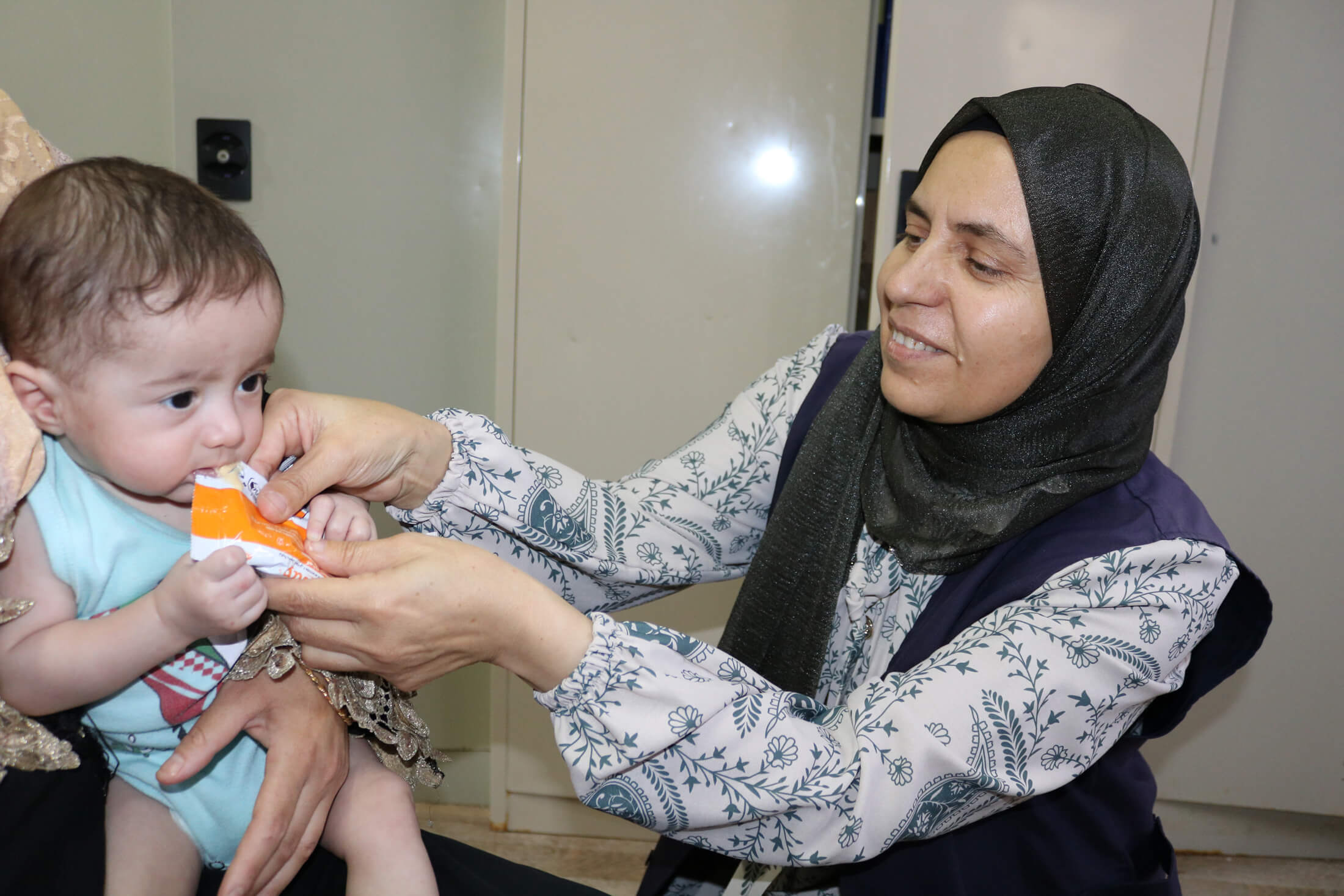 An International Medical Corps Nutrition Volunteer checks an infant for malnutrition and feeds them a nutrient-dense therapeutic food called Plumpy’Nut.