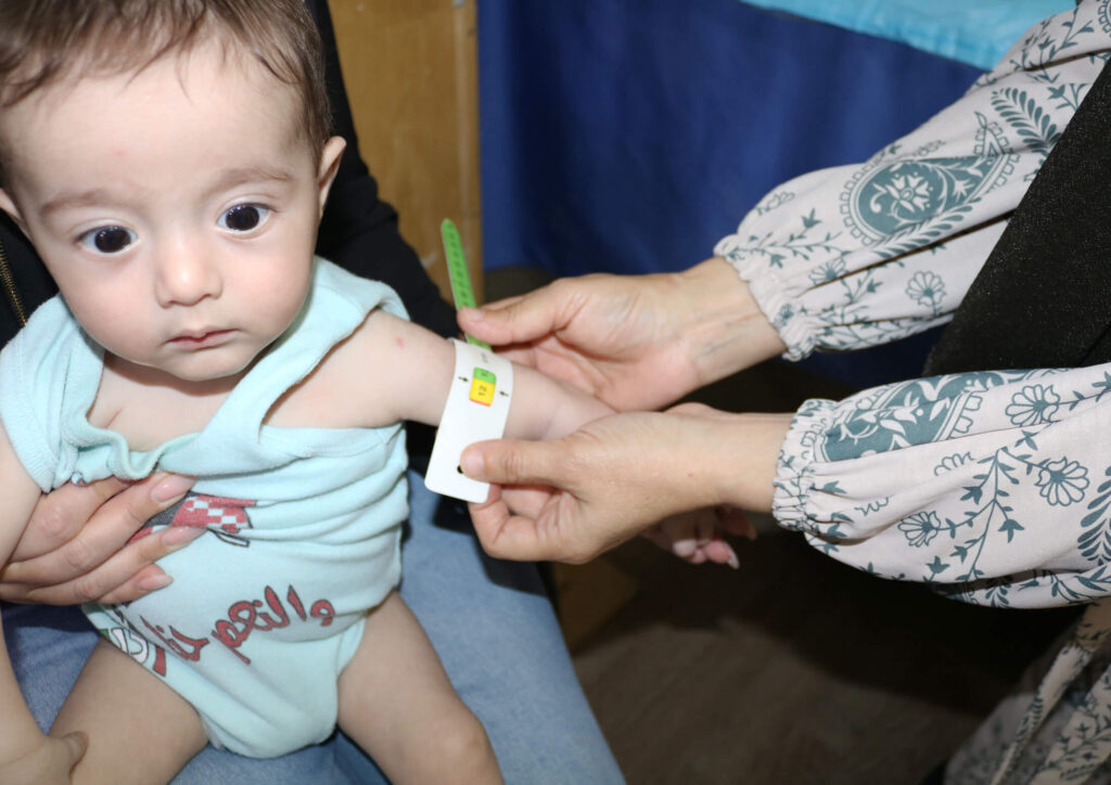 Hamida Alayan Al-Mohammed measures the MUAC of a child at an International Medical Corps nutrition clinic in Jordan’s Zaatari refugee camp. Taking MUAC measurements of children is one of her regular tasks during a typical workday.