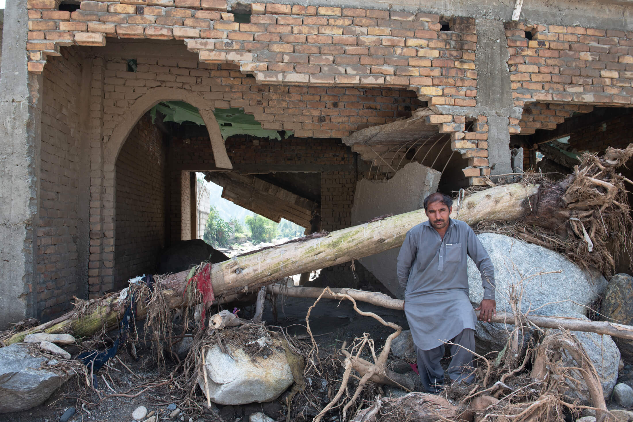 Fazl il Ghani stands in front of his home, which was severely damaged in the flooding.