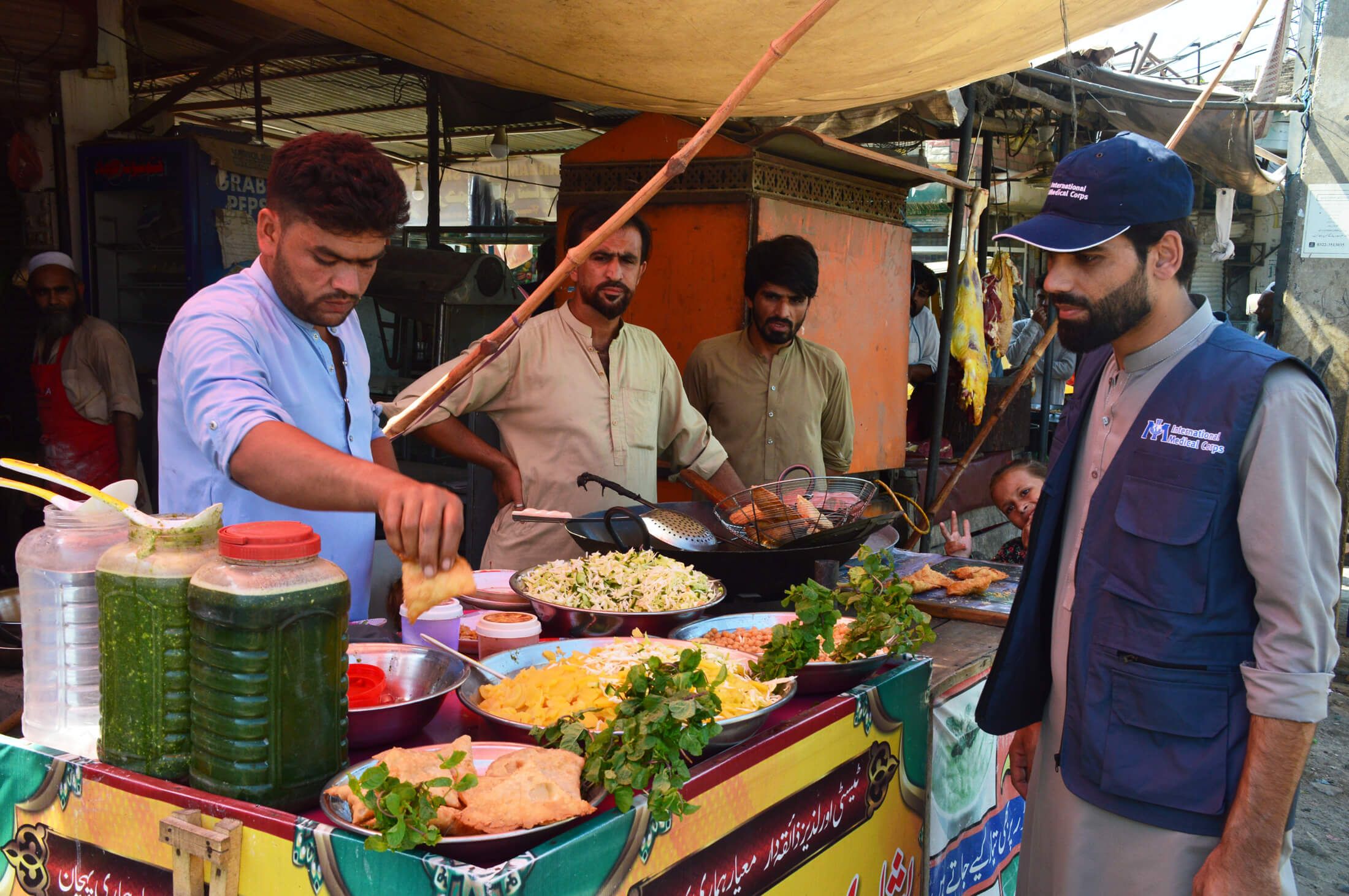 Faiz Ullah visits Zahid (left) at his samosa and chaat stall in the local bazaar.